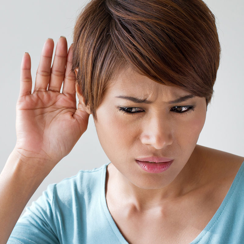 Woman holding hand to ear in an attempt to hear better.