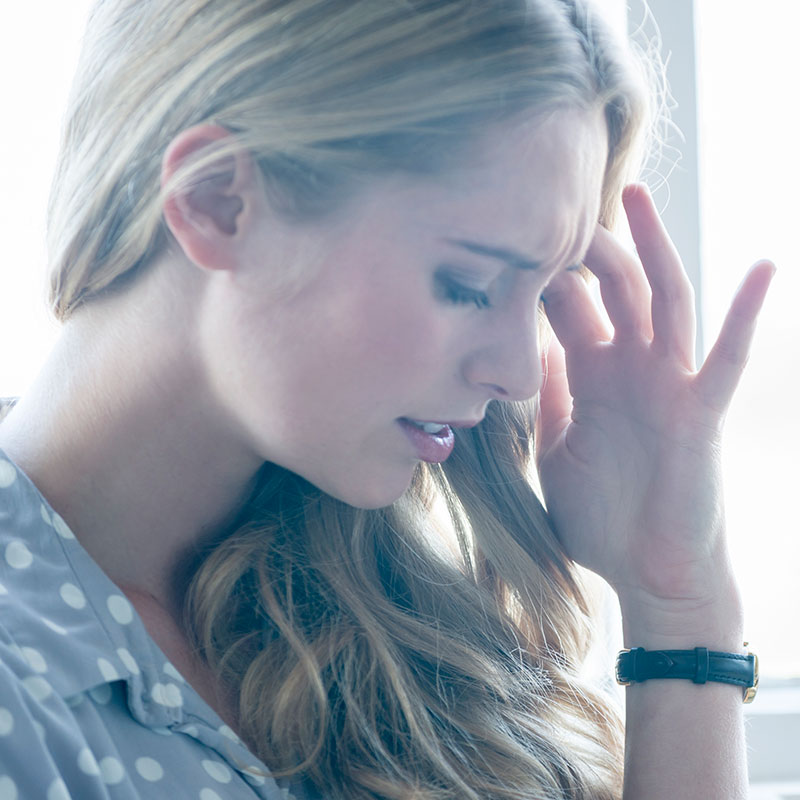 Woman holding her head because she has a headache.