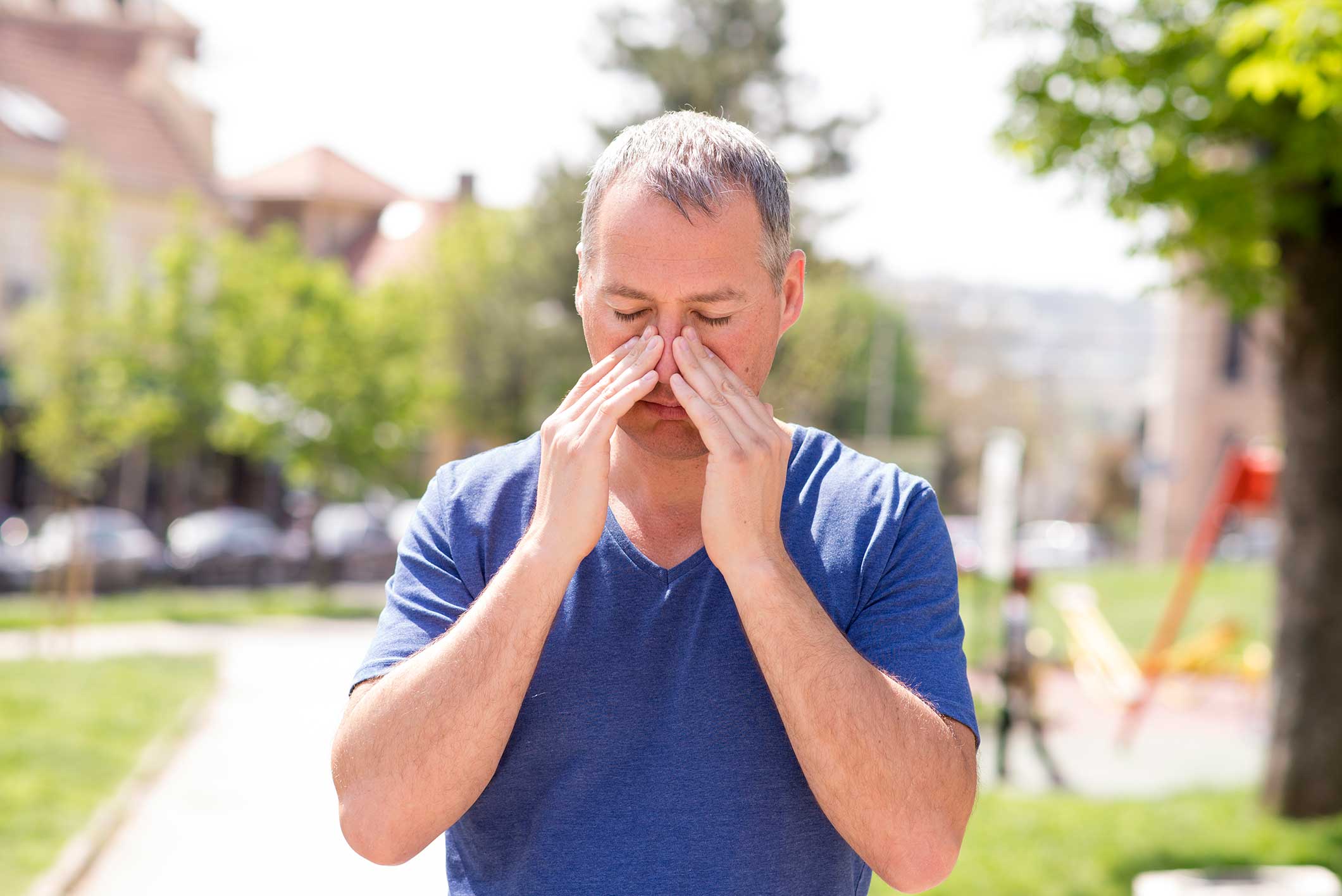A man holding his face trying to relief sinus pressure.