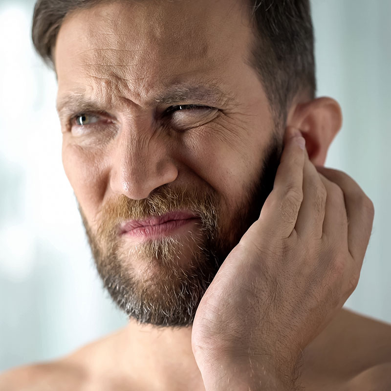 Man holding ear in pain because he has an ear infection. 